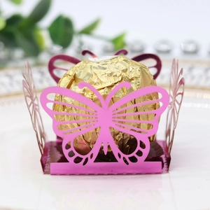 Macro shot of laser-cut butterfly candy box in magenta with gold wrapped chocolate