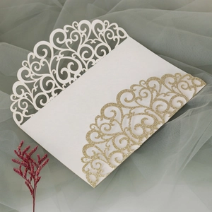 Detailed laser cut lace wedding invitation with sparkling gold glitter accents and floral patterns