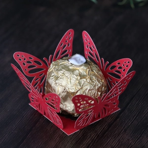 Detail of red laser-cut butterfly lace candy wrapper for chocolates on wood background