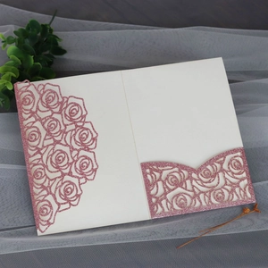 Close-up of laser-cut rose pattern with pink glitter texture on a cream wedding invitation