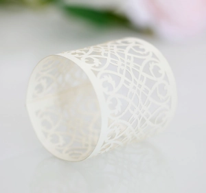 Close-up of laser-cut cream paper napkin ring with elegant floral lace pattern