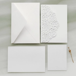 Laser-cut white wedding invitation set with rose hollow design and envelope on soft fabric