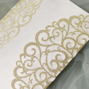Macro detail of laser-cut wedding invitation with elegant gold glitter lace texture