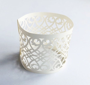Laser-cut cream cupcake wrapper with intricate heart patterns and filigree details