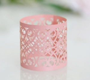 Close-up of pink laser-cut paper napkin ring featuring an elegant floral镂空 pattern