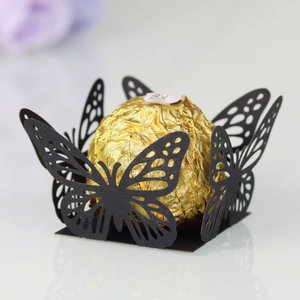 Macro view of black laser cut butterfly truffle wrappers for festive party candy decor