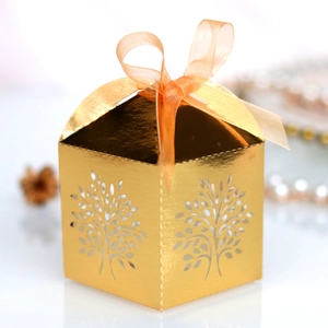 Detail of laser-cut golden tree gift box with elegant orange ribbon and metallic finish