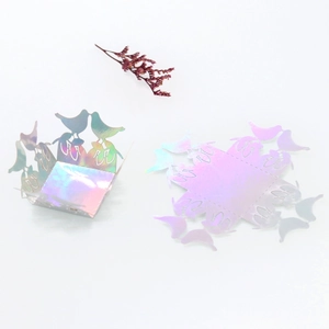 Macro view of laser-cut wedding favor box featuring bird patterns in holographic silver