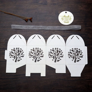 Detail of laser-cut tree gift box with white pearlescent finish and grey ribbon bow