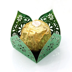 Close-up of laser-cut green pearlescent paper candy wrapper with intricate floral patterns