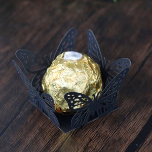 Detail of black laser-cut butterfly candy box holder on a rustic wooden table surface
