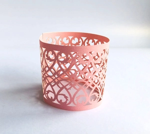 Detailed laser-cut heart pattern on pink decorative cupcake wrapper or candle holder