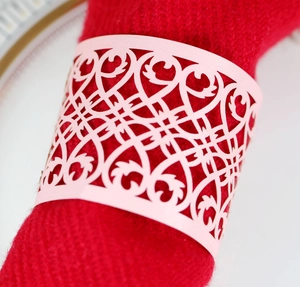 Close-up of laser-cut pink hollow napkin ring with elegant floral scroll patterns