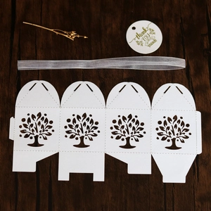 White laser-cut Tree of Life candy box with silver ribbon and thank you tag on wood