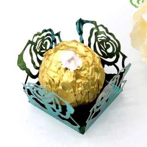 Détail macro du motif rose découpé au laser sur boîte à chocolat métallique verte