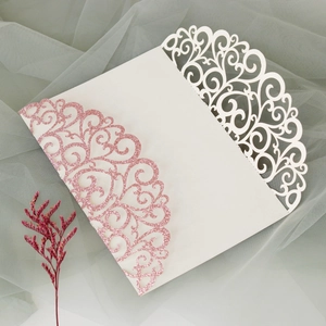 Detail of laser-cut off-white wedding invitation with pink glitter vine patterns
