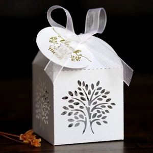 Detail of white laser-cut tree gift box with elegant ribbon and Thank You tag on wood