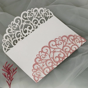Detail of laser cut wedding invitation cover with white cardstock and pink glitter finish