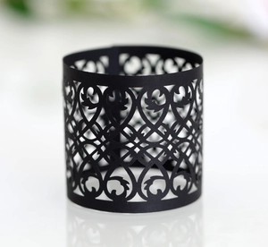 Detail showing laser-cut black matte paper napkin ring with intricate hollow floral patterns