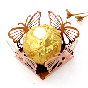Macro shot of rose gold laser-cut butterfly candy box holding a chocolate truffle