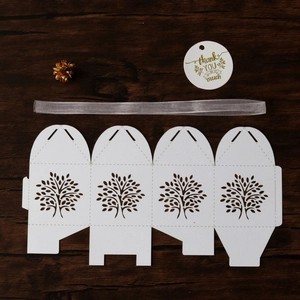 Flat lay of laser-cut Tree of Life candy box with silver ribbon and thank you tag