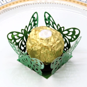 Detail of green laser-cut butterfly chocolate wrapper on a white and gold ceramic plate