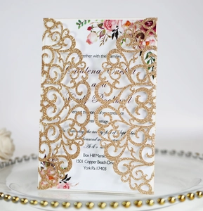 Detail of laser-cut wedding invitation with gold glitter case and floral inner page