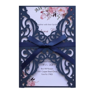 Detail of navy blue laser-cut wedding invitation with silk ribbon bow and floral insert