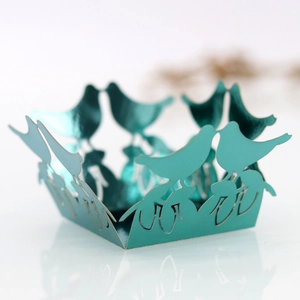 Macro shot of laser-cut teal bird candy box showing intricate floral hollow details