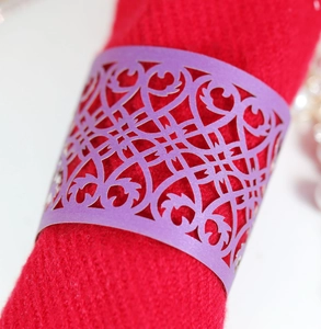 Detailed close-up of purple laser-cut paper napkin rings with floral hollow patterns