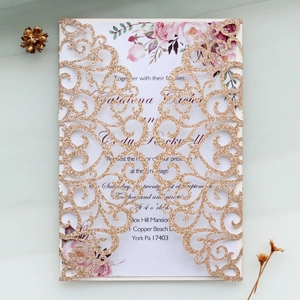 Detail of laser-cut rose gold glitter wedding invitation with floral inner card
