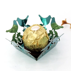Macro detail of laser-cut green metallic candy box featuring bird and leaf patterns