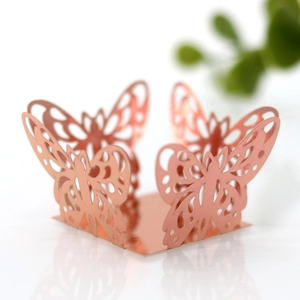 Close-up of rose gold laser-cut butterfly candy box with mirror reflection on white base