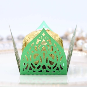 Macro shot of laser-cut green paper box with gold foil chocolate for wedding favors