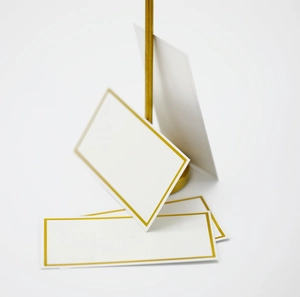 White place cards with gold foil border and matching gold metal stand for wedding tables