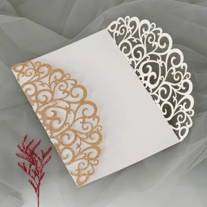 Detail of laser-cut wedding invitation with gold glitter finish and floral pattern