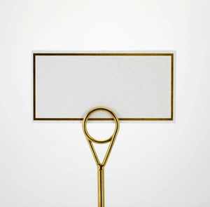 Detailed view of gold metal place card holder with elegant gold-edged white table card