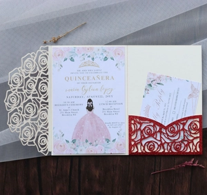 Detail of laser-cut rose wedding invitation set with glitter card on wooden surface