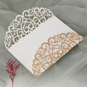Detail of laser-cut cream invitation card with gold glitter vine hollow patterns