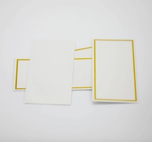 Macro detail of white wedding place cards with elegant gold foil borders for table seating