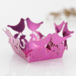 Macro detail of magenta laser-cut bird cupcake wrapper with pearl paper shimmer
