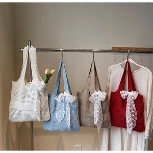 Détail de sacs fourre-tout tricotés en quatre couleurs avec nœuds en dentelle blanche