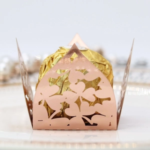 Detail of rose gold laser-cut candy box with elegant floral patterns on white plate
