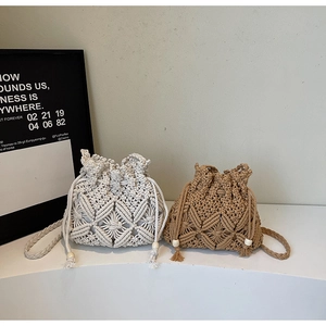 Detail of woven bucket bags with tassel drawstrings and geometric patterns on white pedestal