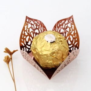 Macro shot of rose gold laser-cut chocolate wrapper with elegant vine hollow pattern