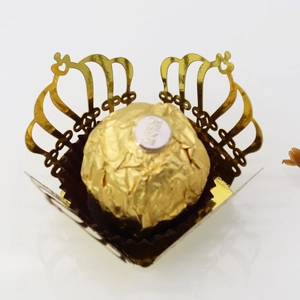 Macro shot of laser-cut gold crown chocolate wrapper showing intricate hollowed lace detail