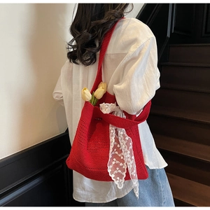 Gros plan du sac bandoulière en tricot rouge avec ruban de dentelle blanche et texture