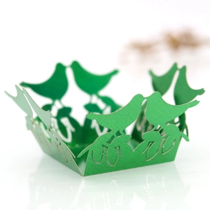 Macro detail of laser-cut green cupcake wrapper with love birds and floral patterns