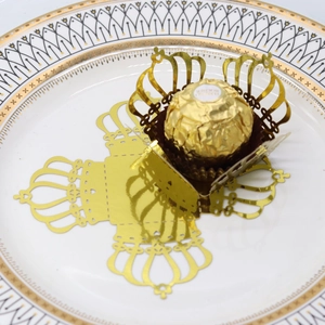 Detail of laser-cut gold crown chocolate wrappers with elegant hollow pattern for party