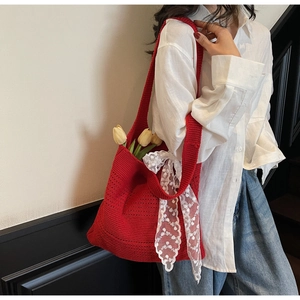 Détail du sac cabas rouge en maille avec un grand nœud en dentelle blanche et bandoulière